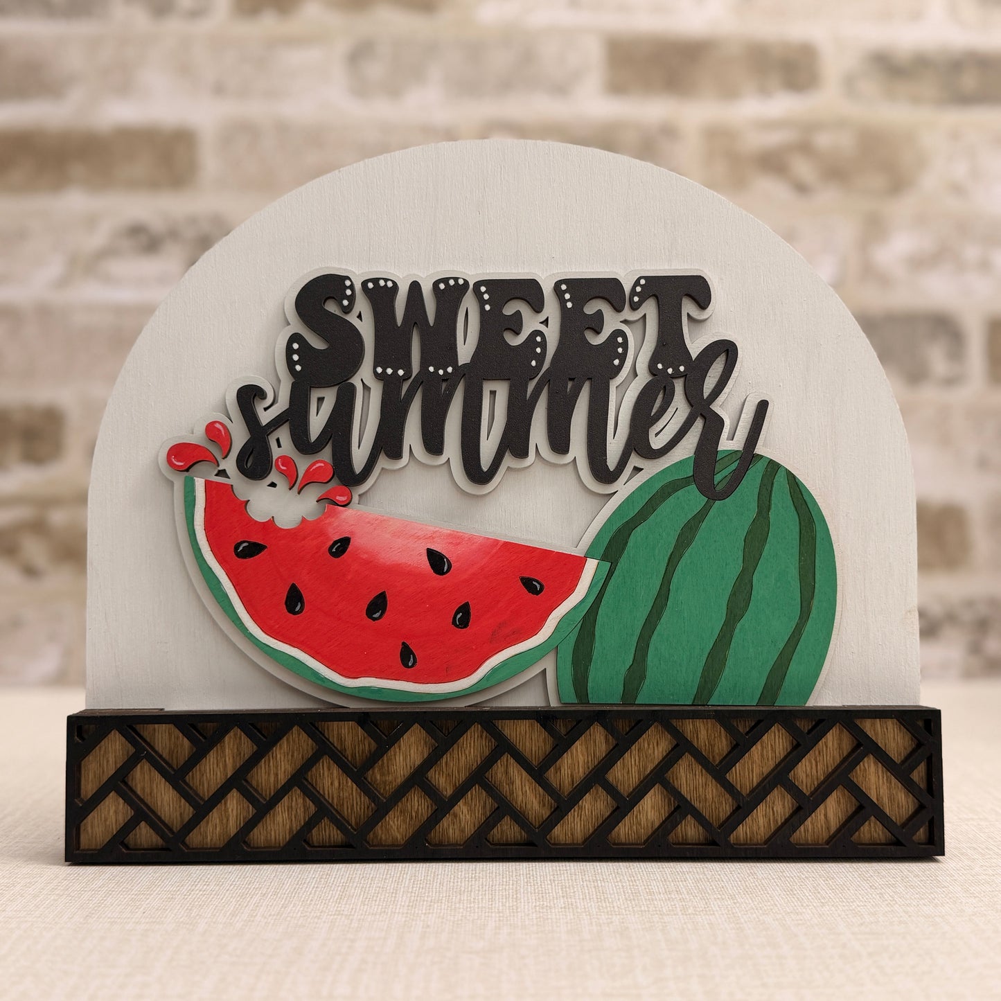Decorative sign with 'Sweet Summer' text and watermelon graphics on a textured surface.