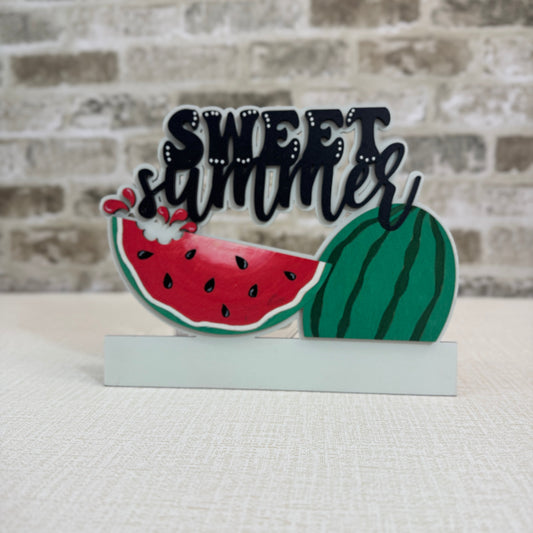 Decorative sign with watermelon design and 'Sweet Summer' text on a textured surface.
