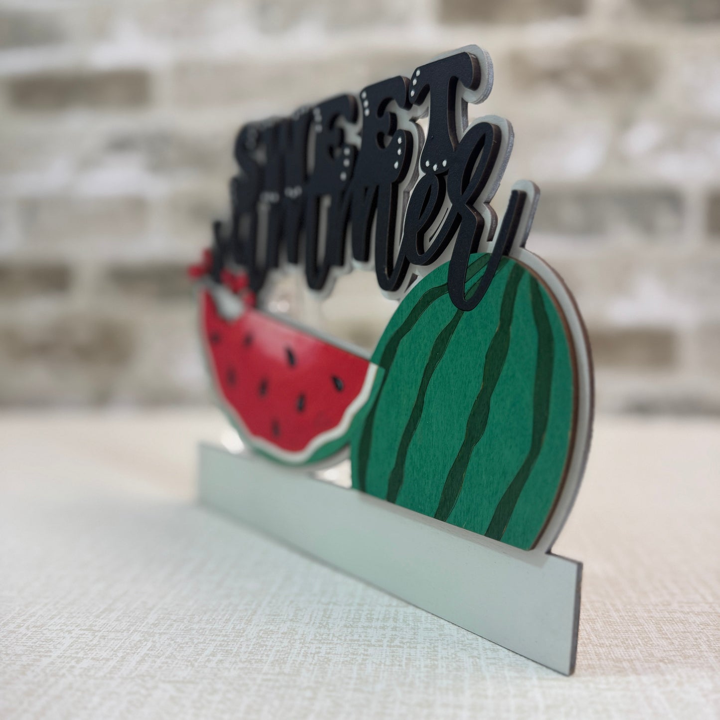 Decorative stand with watermelon design and 'Happy' text against a blurred background